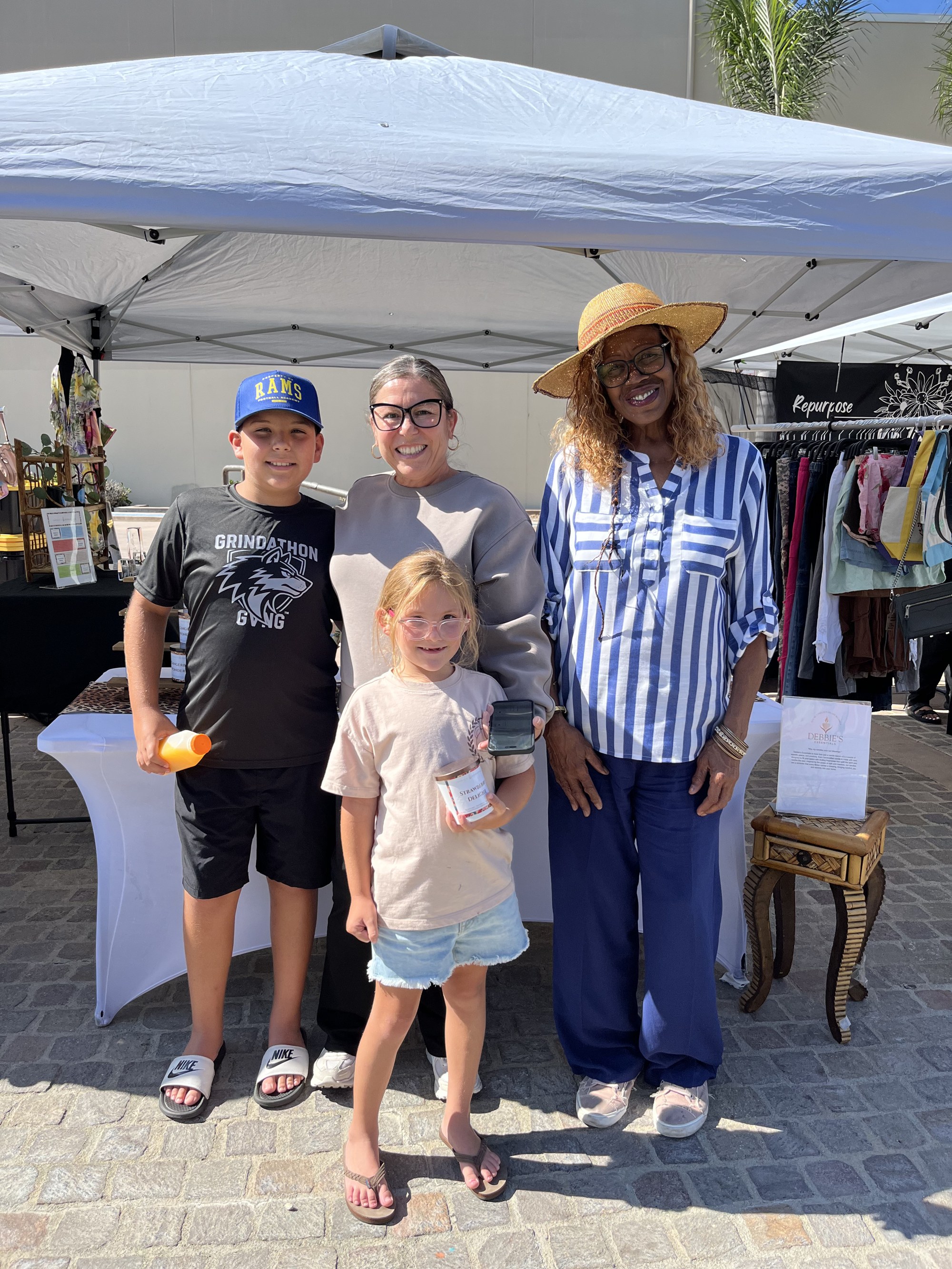 Debbie posing with a mother and her two children holding a Strawberry Delight candle